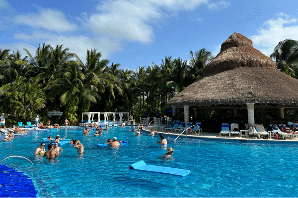 Paradise Beach Cozumel pool with swim-up bar hut, palm trees, and lounge chairs in a tropical setting.